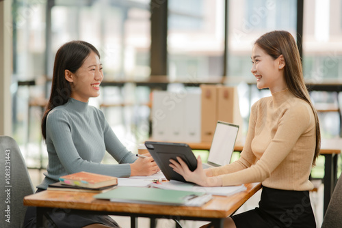 Two Asian businesswomen working with documents in an office.