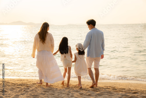 Happy Asian family on holiday vacation.  Father, Mother with two children enjoying sunrise on beach.