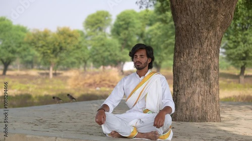 young Indian yogi doing his yoga mediation practices on hills rocks in forest