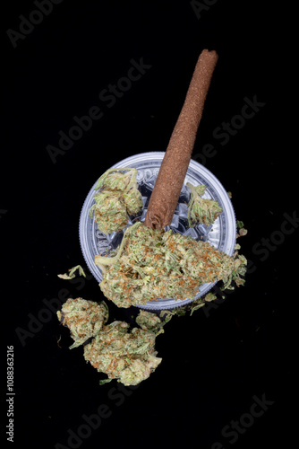 Medical cannabis buds are dried flowers used for therapeutic benefits, rich in THC, CBD, and terpenes. presented with prerolled joint and grinder against black background. Vertical 