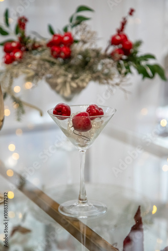 A glass of wine with three cherries in it sits on a table