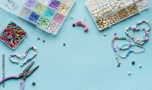 Obraz na płótnie Colorful assortment of beads and jewelry-making tools on a blue surface with completed bracelets w salonie