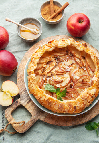 Delicious homemade apple tart displayed on a wooden board surrounded by fresh apples and honey