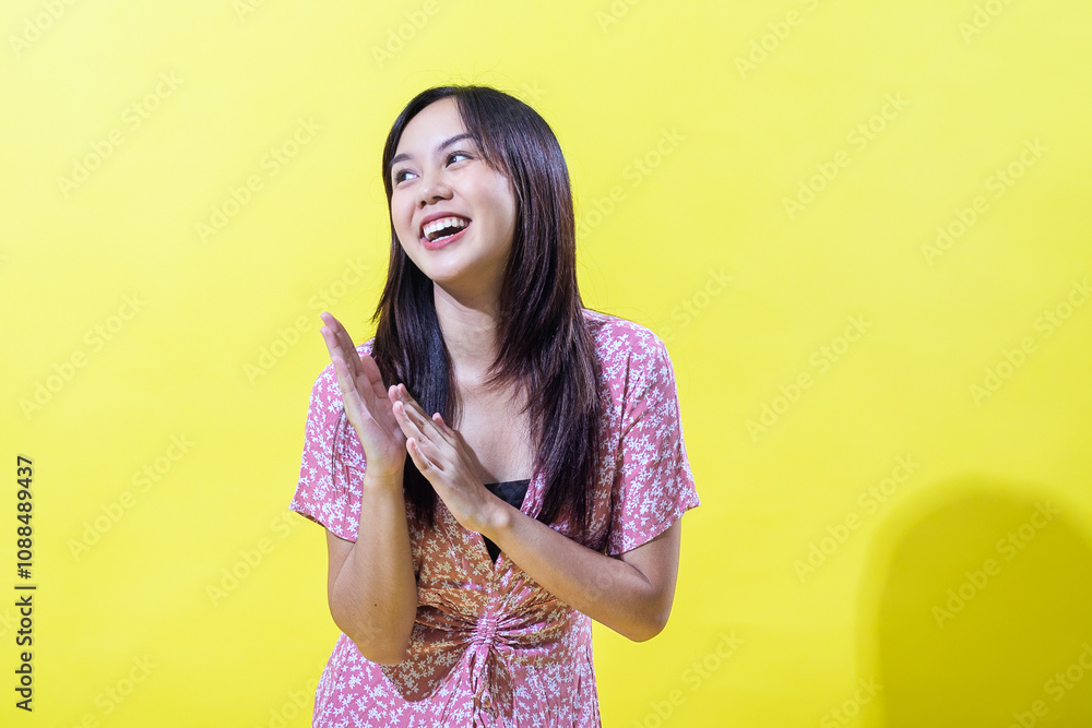 Indonesian Asian woman in a pink floral dress, smiling brightly against a yellow background. Bright, even lighting. Indonesian Asian woman in a pink floral dress, smiling brightly against a yellow background. Bright, even lighting.