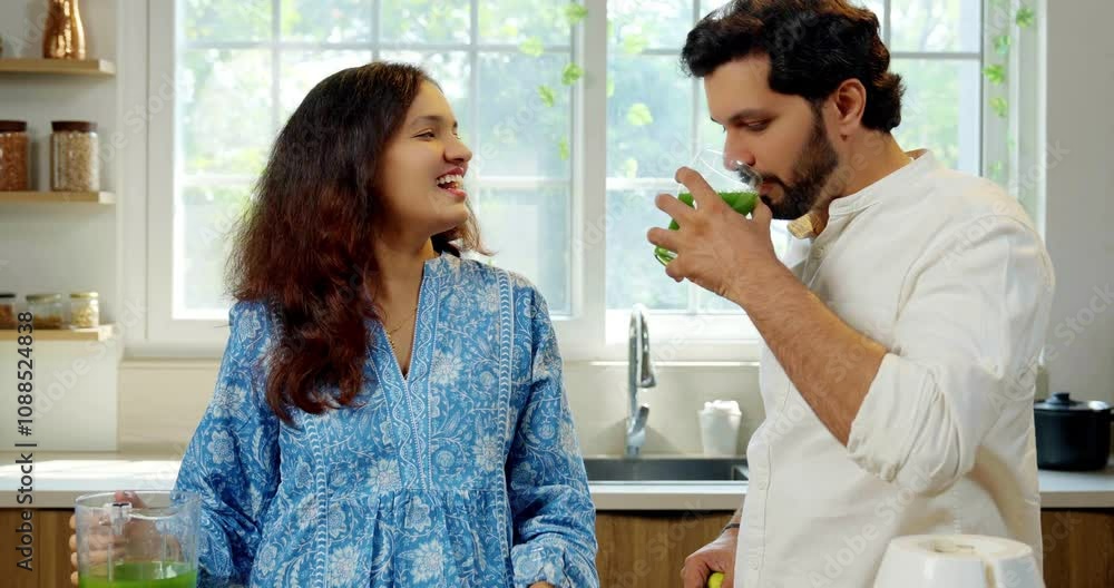 Indian young wife preparing fresh green spinach juice and serving it to her husband in kitchen, focusing on health and nutrition concept for a healthy lifestyle Indian young wife preparing fresh green spinach juice and serving it to her husband in kitchen, focusing on health and nutrition concept for a healthy lifestyle