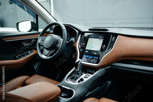 Modern brown car interior, leather steering wheel, climate control, large navigation screen, air ducts, deflectors on the car panel. Interior details.