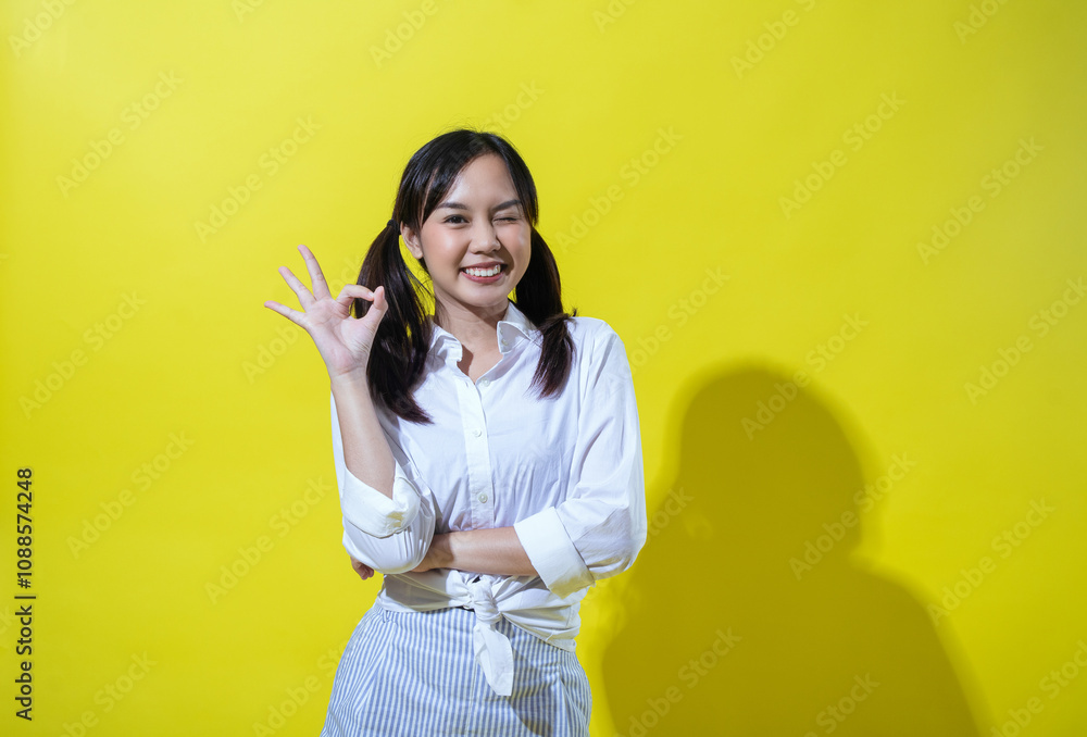 Asian woman with pigtails in a white shirt and striped pants, making an Asian woman with pigtails in a white shirt and striped pants, making an