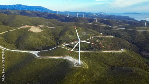 Drone view above green hills with wind turbines, future with creating emission-free clean energy