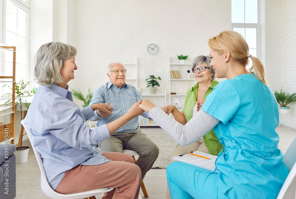 Group of senior people sitting in circle at nursing home holding hands with young nurse together during psychological therapy in session. Psychotherapy and support for elderly retired people concept. Group of senior people sitting in circle at nursing home holding hands with young nurse together during psychological therapy in session. Psychotherapy and support for elderly retired people concept.