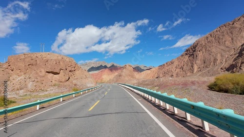 Driving on asphalt road passing through Gobi desert with colorful mountains on sunny autumn day in southern Xinjiang, China, POV from the car, 4k real time footage, travel concept. photo