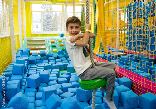 Cute cheerful boy playing from in entertainment center. photo