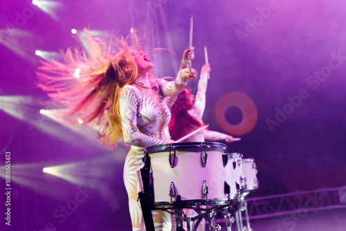 Group of female drummers in stage costumes in the circus arena in the light of spotlights and smoke. photo