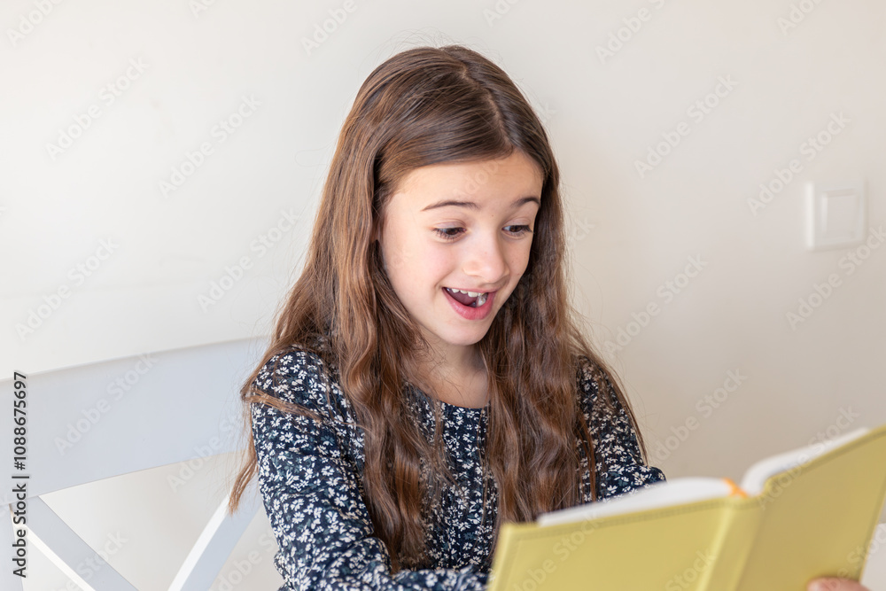 Happy girl reading a book at home. The girl is preparing for lessons at school