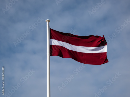 Fotografie The national flag of Latvia in the wind with cloudy sky