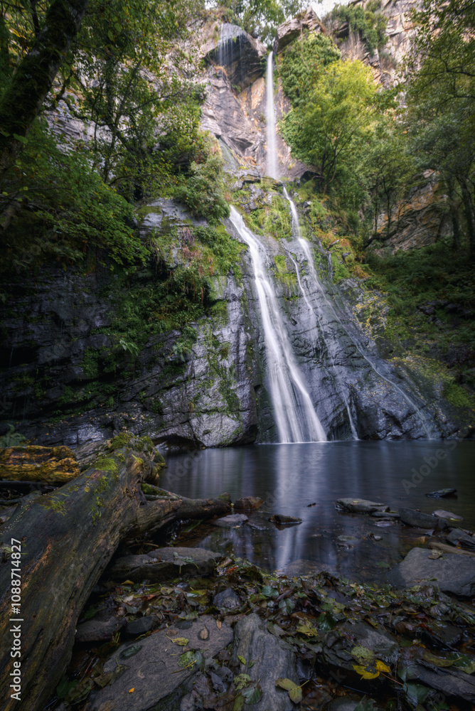 Obraz premium A waterfall falls in two stages over a quiet pool
