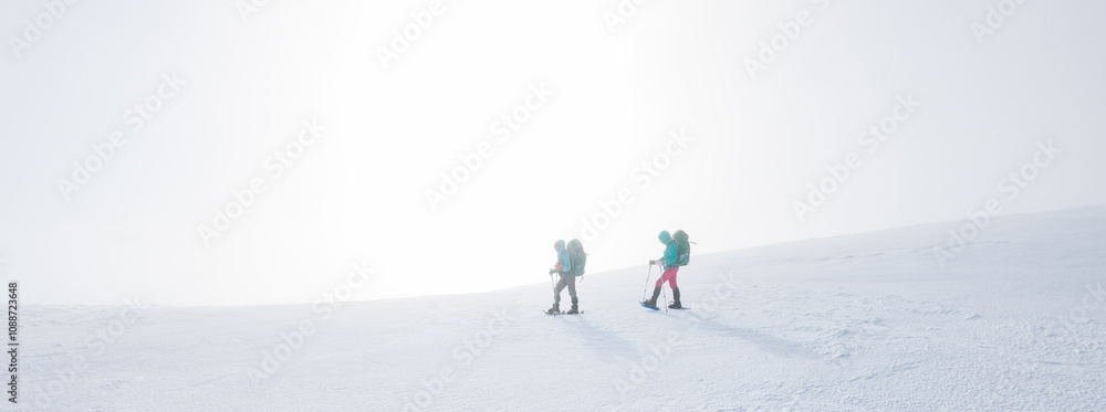 climbers climb the mountain in the snow. Winter mountaineering. two girls in snowshoes walk through the snow. mountaineering equipment. hiking in the mountains in winter. climbers climb the mountain in the snow. Winter mountaineering. two girls in snowshoes walk through the snow. mountaineering equipment. hiking in the mountains in winter.
