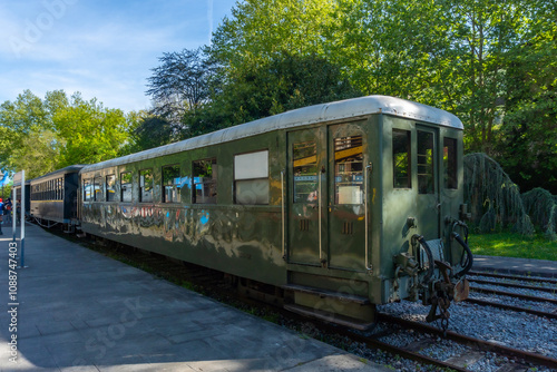 A train is parked on the tracks with a green car