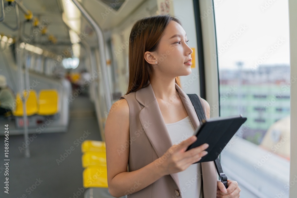 Asian Woman Using Digital Tablet While Commuting In A Skytrain Asian Woman Using Digital Tablet While Commuting In A Skytrain