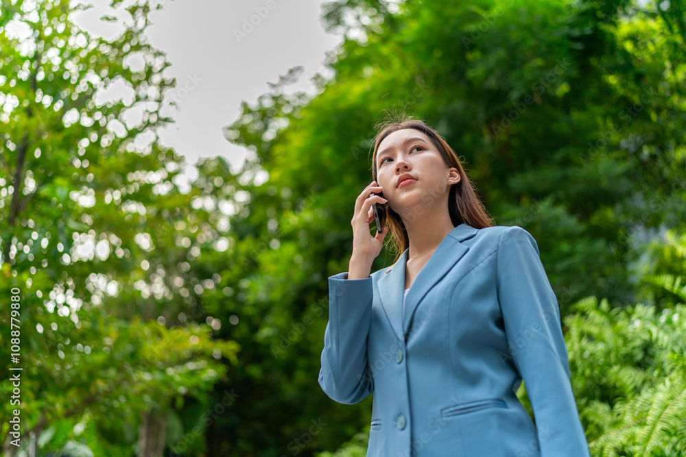 Young Businesswoman In Blue Suit Using Phone Amid Greenery of A Park In The City Young Businesswoman In Blue Suit Using Phone Amid Greenery of A Park In The City