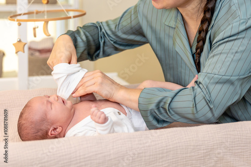 Mother wearing clothes to her baby. Baby healthcare hygiene concept.