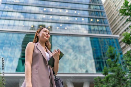 Asian Businesswoman Using Tablet In Front of A Modern Office Building In the Financial District