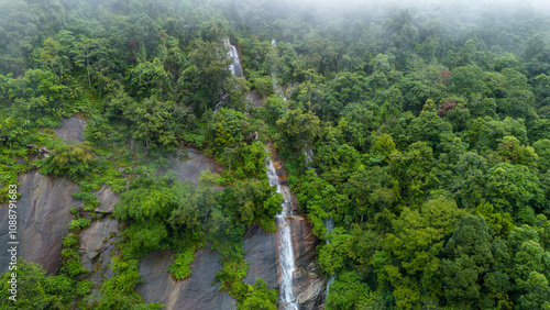 Aerial view of beautiful waterfall village in the lush green rain cloud and foggy cover tropical rain forest mountain during the rainy season. Beautiful landscape with high mountain photo