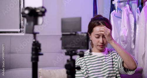 A female influencer creator feels exhausted from live streaming clothes sale online for long hours. She takes a break to recharge for more selling photo