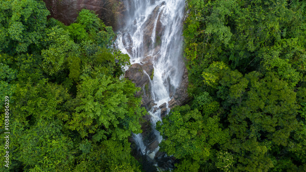Aerial view of beautiful waterfall village in the lush green rain cloud and foggy cover tropical rain forest mountain during the rainy season. Beautiful landscape with high mountain Aerial view of beautiful waterfall village in the lush green rain cloud and foggy cover tropical rain forest mountain during the rainy season. Beautiful landscape with high mountain