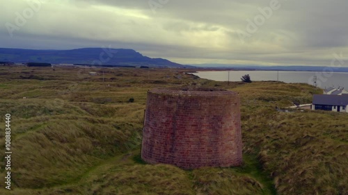 Aerial orbit around Magilligan Martello Tower, showcasing the surrounding landscape photo