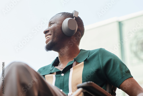 Foto Candid low angle shot of young man with disability wearing headphones and listen