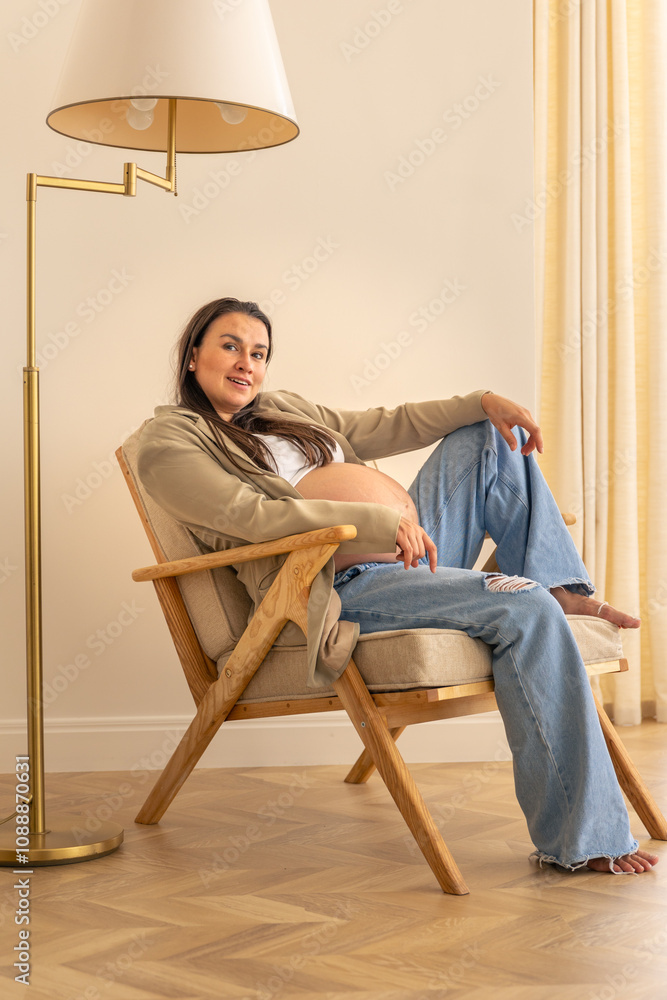 Stylish pregnant woman in the room on a chair. Concept of style and pregnancy. Stylish pregnant woman in the room on a chair. Concept of style and pregnancy.