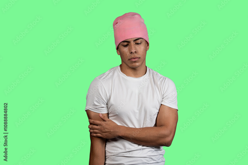 Young latino man wearing pink beanie and white t-shirt on green background contemplating Young latino man wearing pink beanie and white t-shirt on green background contemplating