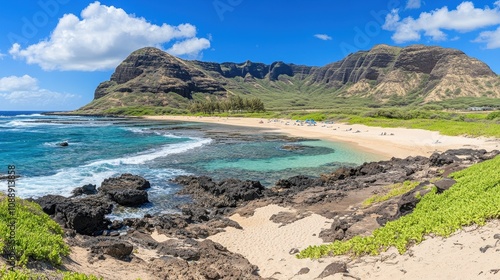 Panoramic view of a secluded beach with turquoise water, volcanic rock formations, and mountains under a vibrant blue sky.