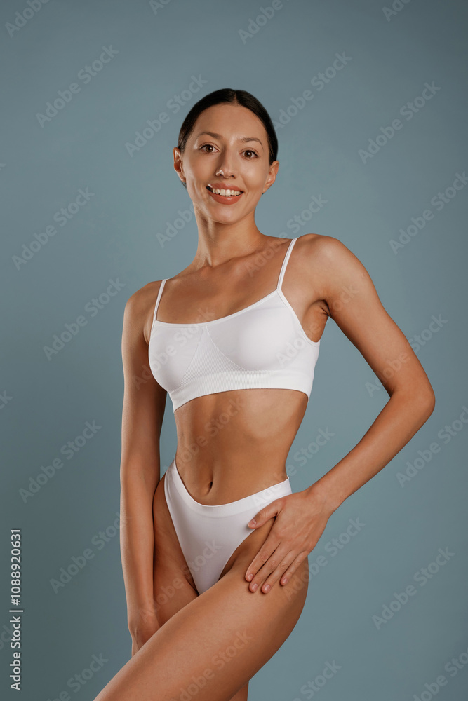 Fitness model is in white underwear. Young woman is in the studio against background Fitness model is in white underwear. Young woman is in the studio against background