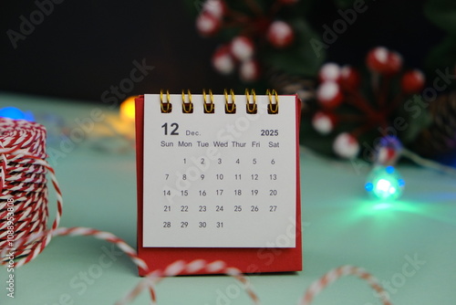 Monthly desk calendar for December 2024 year on wooden table with black alarm clock. photo