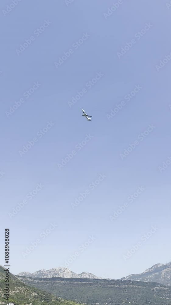 Airplane soaring above a coastal landscape with mountain backdrop.