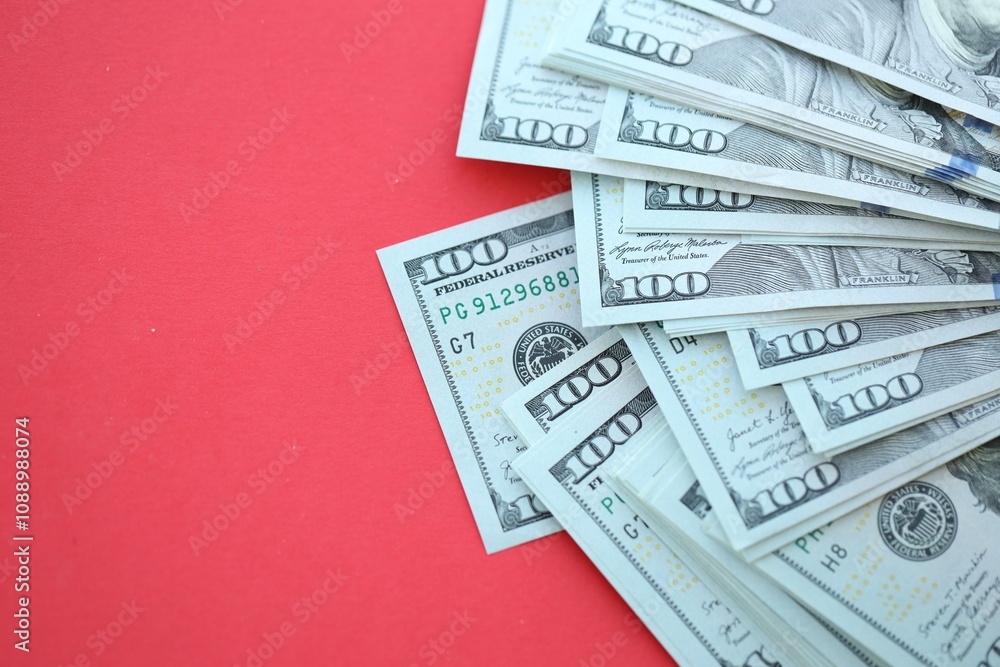 Big amount of hundred dollar bills in thick stack lies on bright red color paper background Big amount of hundred dollar bills in thick stack lies on bright red color paper background