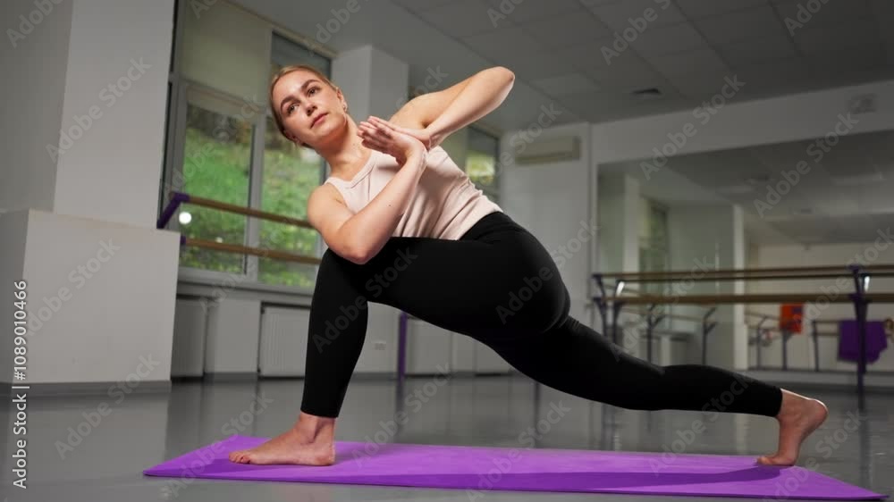 in the studio of spiritual development master class in yoga young girl in a bright room on purple mat in the pose of asana with folded hands and spread legs in the studio of spiritual development master class in yoga young girl in a bright room on purple mat in the pose of asana with folded hands and spread legs