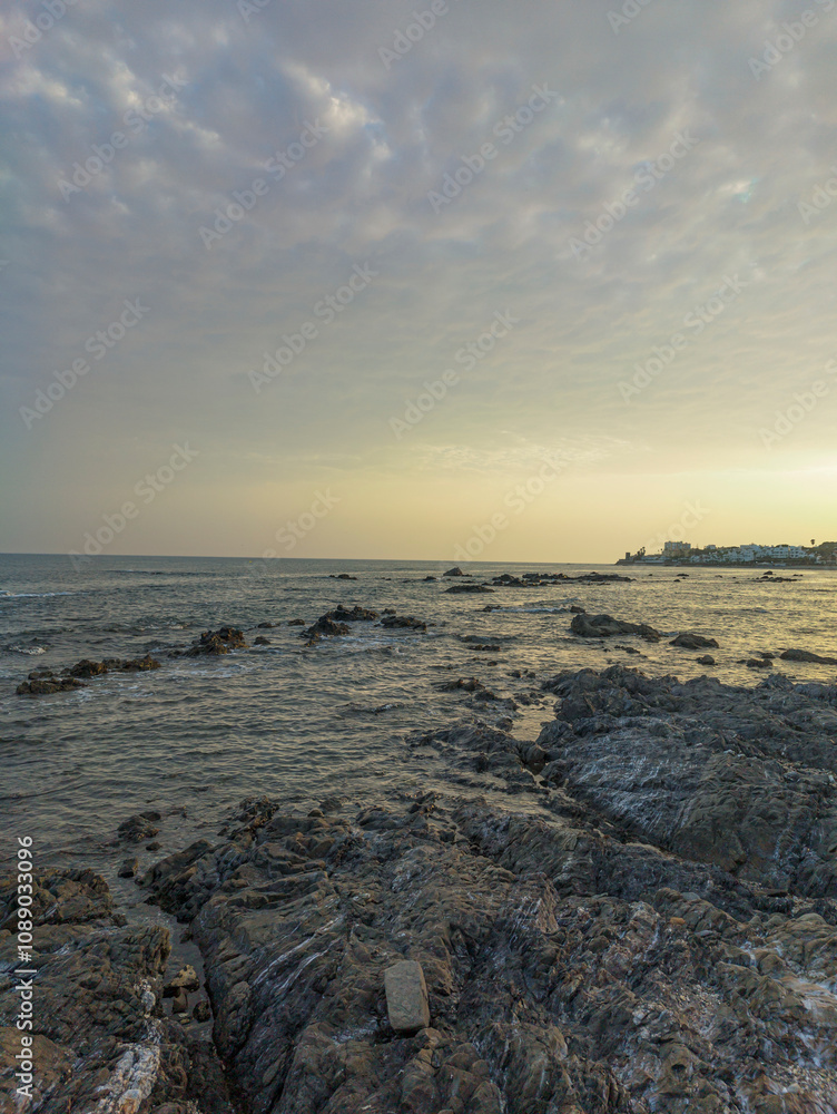 Obraz premium Rocky Beach in Málaga at Sunset with Calm Waves and Soft Sky