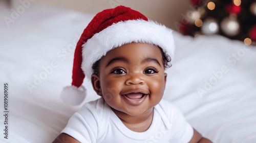 Adorable child wearing a bright red Santa hat displays a joyful smile, set against a soft monochrome background ideal for capturing the essence of the Christmas and New Year festivities