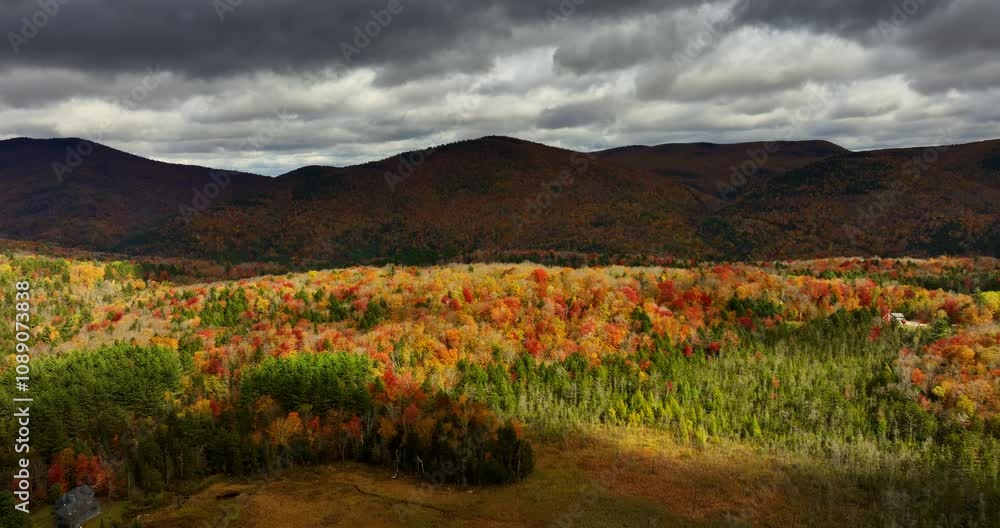 Flight above the beautiful autumn forest in Vermont, New England, USA. Mountains covered by dramatic cloudscape at backdrop. Aerial view. Flight above the beautiful autumn forest in Vermont, New England, USA. Mountains covered by dramatic cloudscape at backdrop. Aerial view.