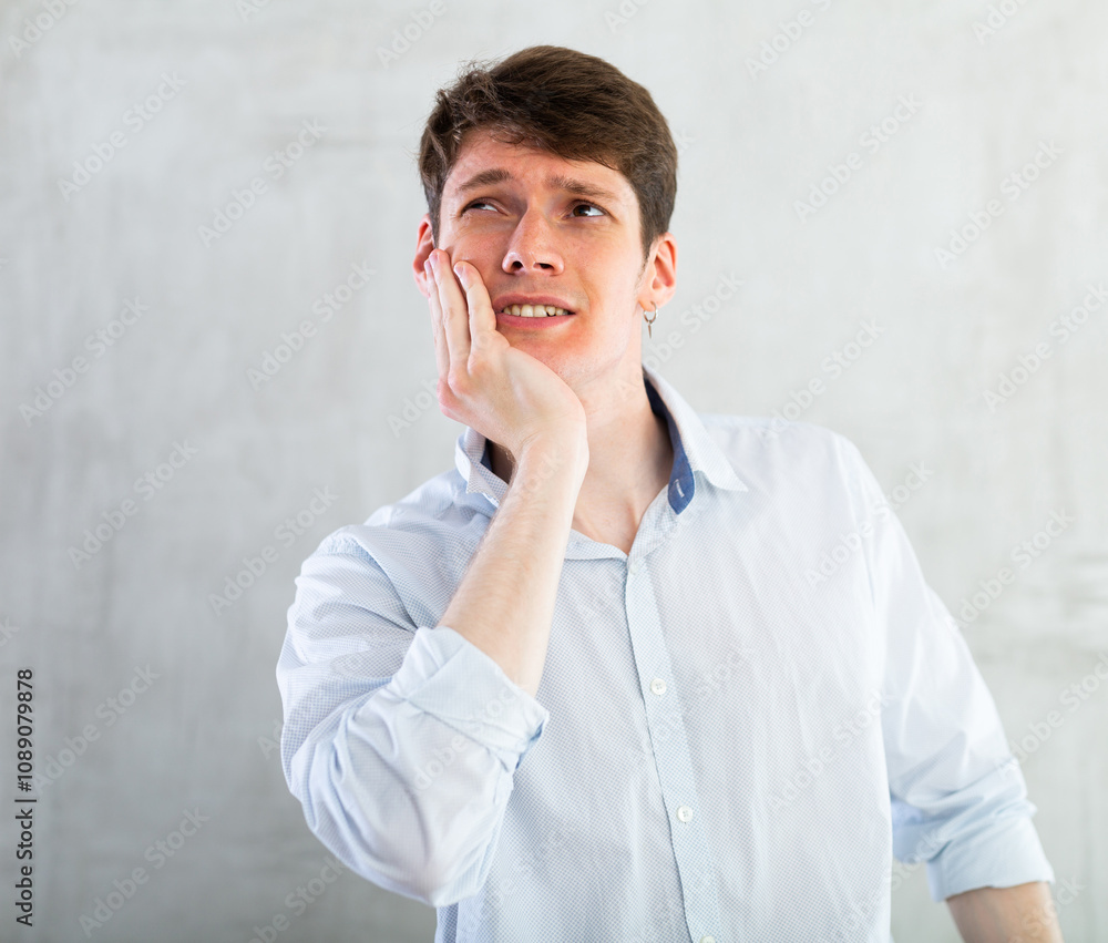 Unhappy man having a toothache in living room Unhappy man having a toothache in living room