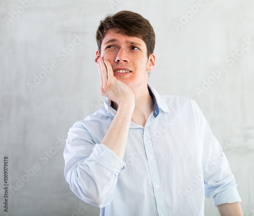 Unhappy man having a toothache in living room