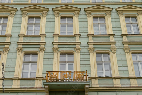 Wallpaper Mural The facade of an old, historic building showcases a striking green paint job, embellished with intricate decorative windows, and features a lovely balcony that adds to its charm and character Torontodigital.ca