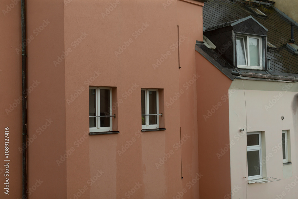 A distinctive pink residential building is showcased, featuring unique and creative window designs along with an impressive architectural style for its roof, all contributing to its charm A distinctive pink residential building is showcased, featuring unique and creative window designs along with an impressive architectural style for its roof, all contributing to its charm