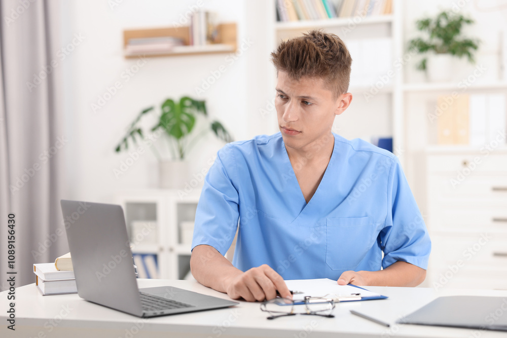 Medical student in uniform studying at table indoors Medical student in uniform studying at table indoors