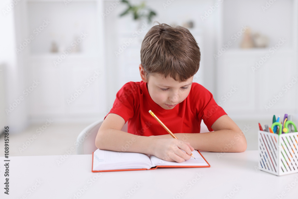 Boy with incorrect posture doing homework at white desk indoors Boy with incorrect posture doing homework at white desk indoors