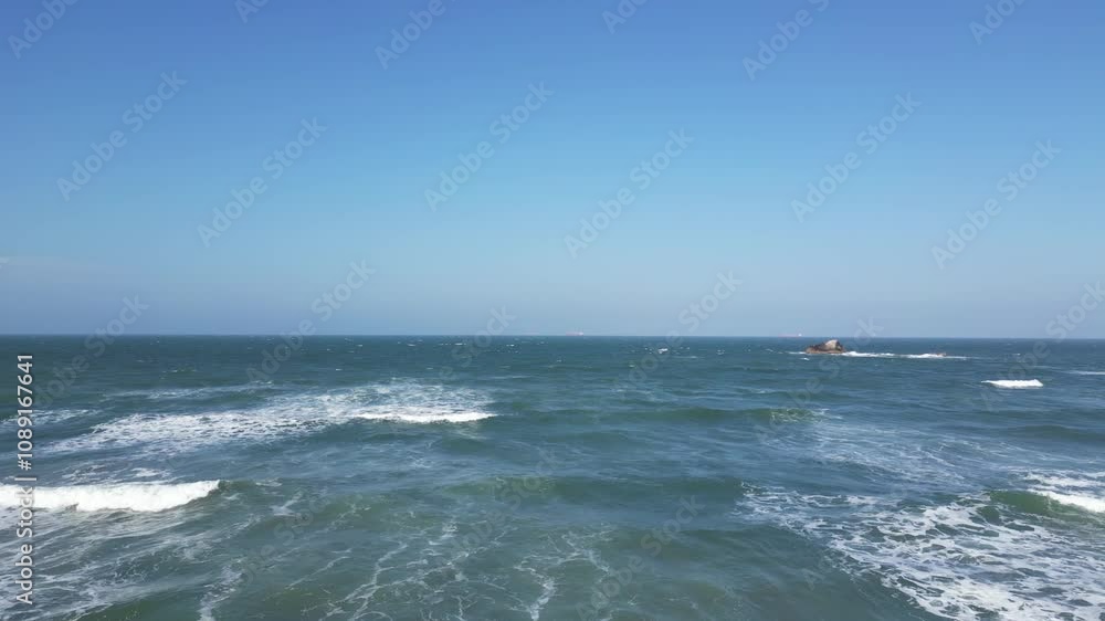 Waves crashing on the shore under a clear blue sky Waves crashing on the shore under a clear blue sky