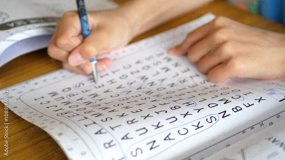 Close up of a kid solving a word search puzzle Close up of a kid solving a word search puzzle
