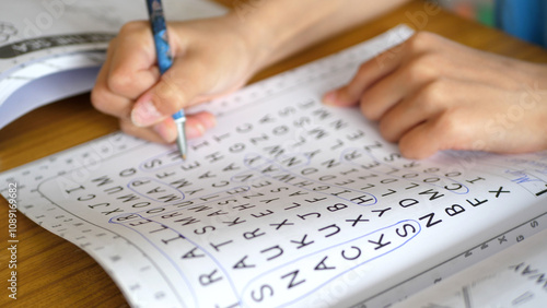 Close up of a kid solving a word search puzzle